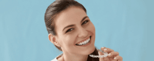 Woman holding her invisalign aligners, smiling at the camera.