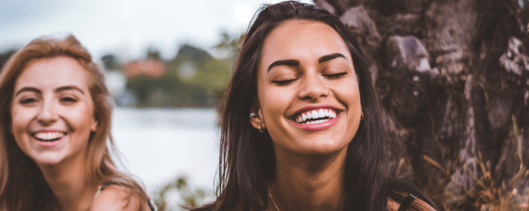 brunette woman outside smiling after her tooth healing.